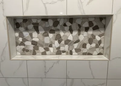 recessed shower niche with stone pebble accent